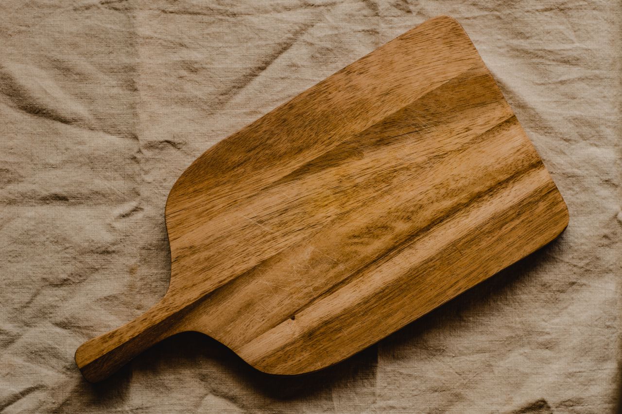 Rustic wooden chopping board on textured linen surface for kitchen decor